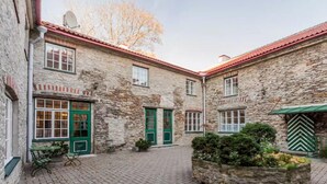 A courtyard with stone buildings, green doors, and a paved area with a planter. - Tallinn City Apartments Toompea Old Town (Tallinn)