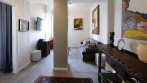 A modern living room with a sofa, a coffee table, and a TV mounted on the wall. There is a large abstract painting on the wall and a small rug on the floor. - MZ Apartments Atlantica posto 6 (Rio de Janeiro)