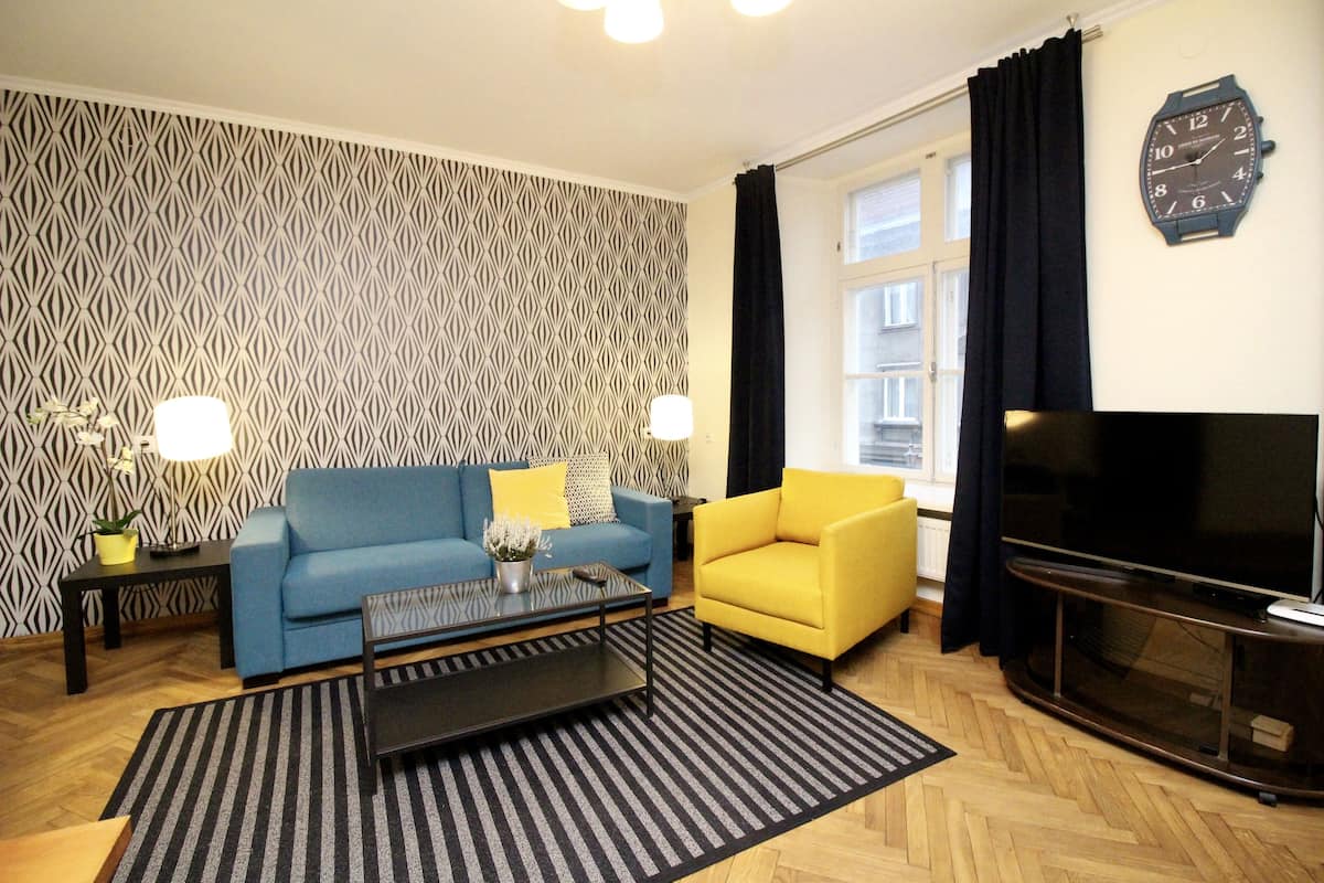 A living room with a blue sofa, yellow armchair, and a TV.