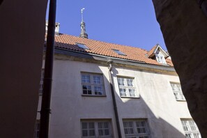 Um edifício com telhado de telhas vermelhas, várias janelas e um girassol.