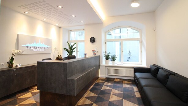 A modern reception area with a reception desk, a black sofa, and a patterned floor.