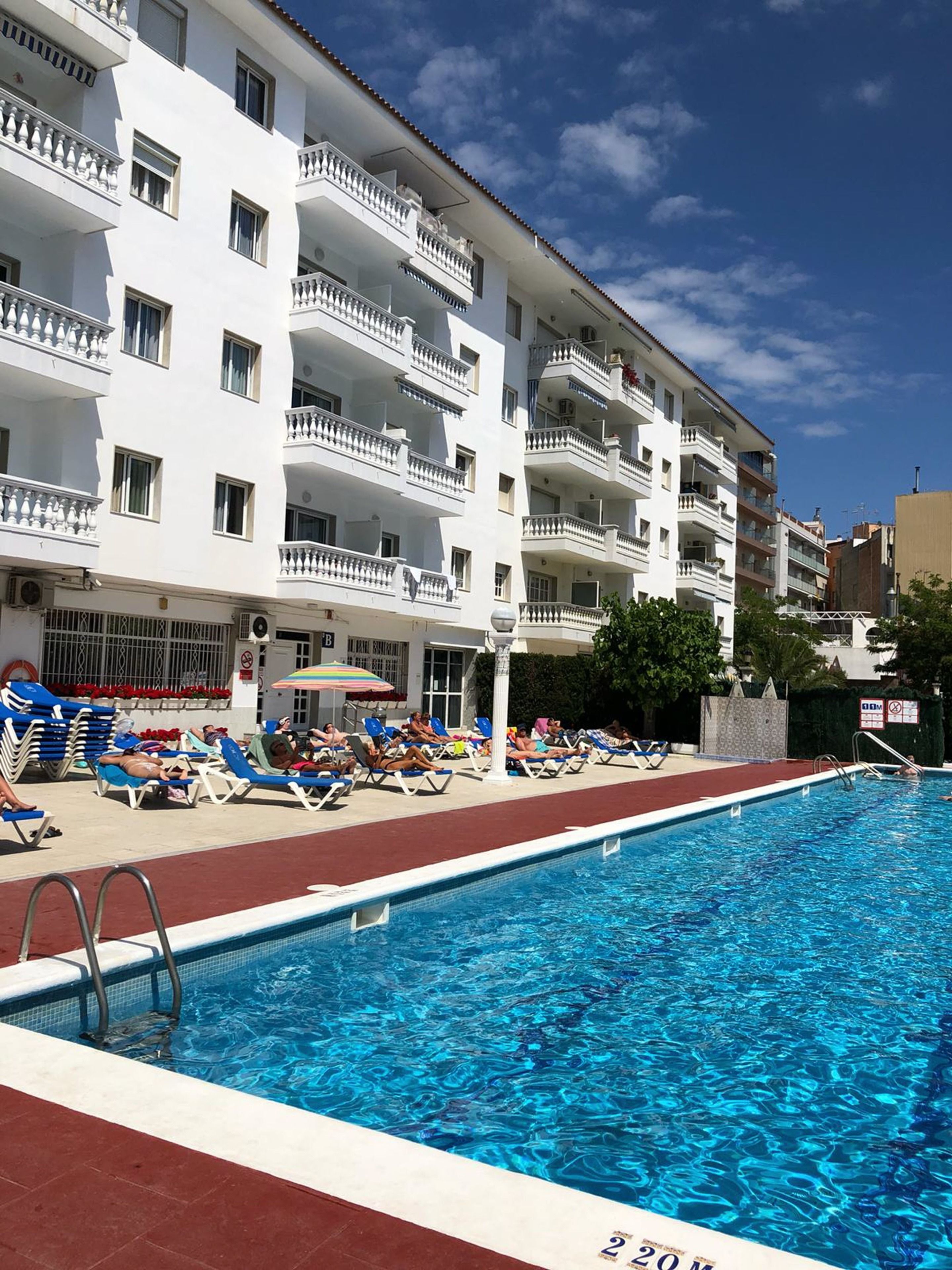 Ein Schwimmbecken mit Liegestühlen und ein Gebäude mit Balkonen.