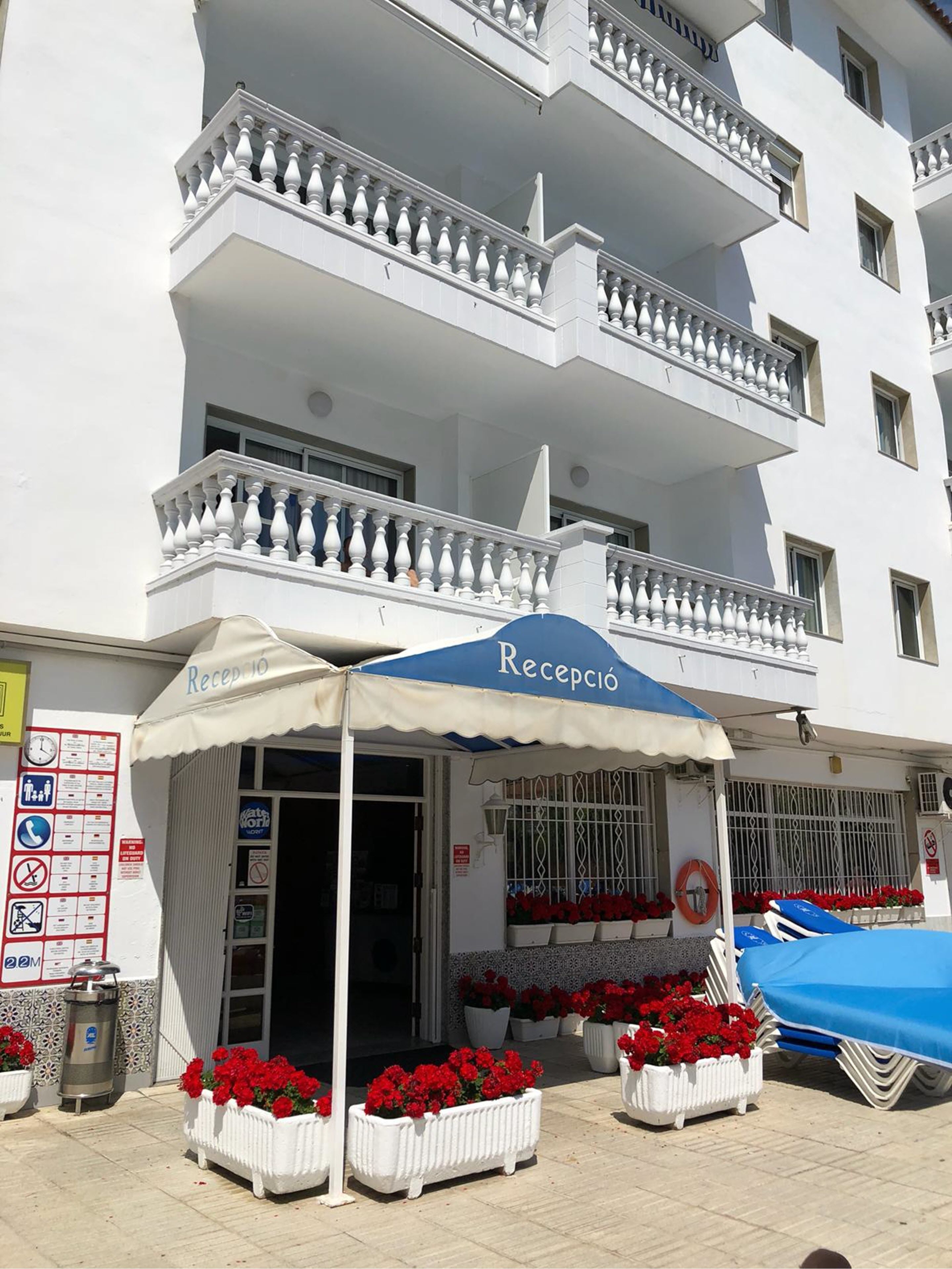 A hotel with a reception area, outdoor seating, and flower arrangements.