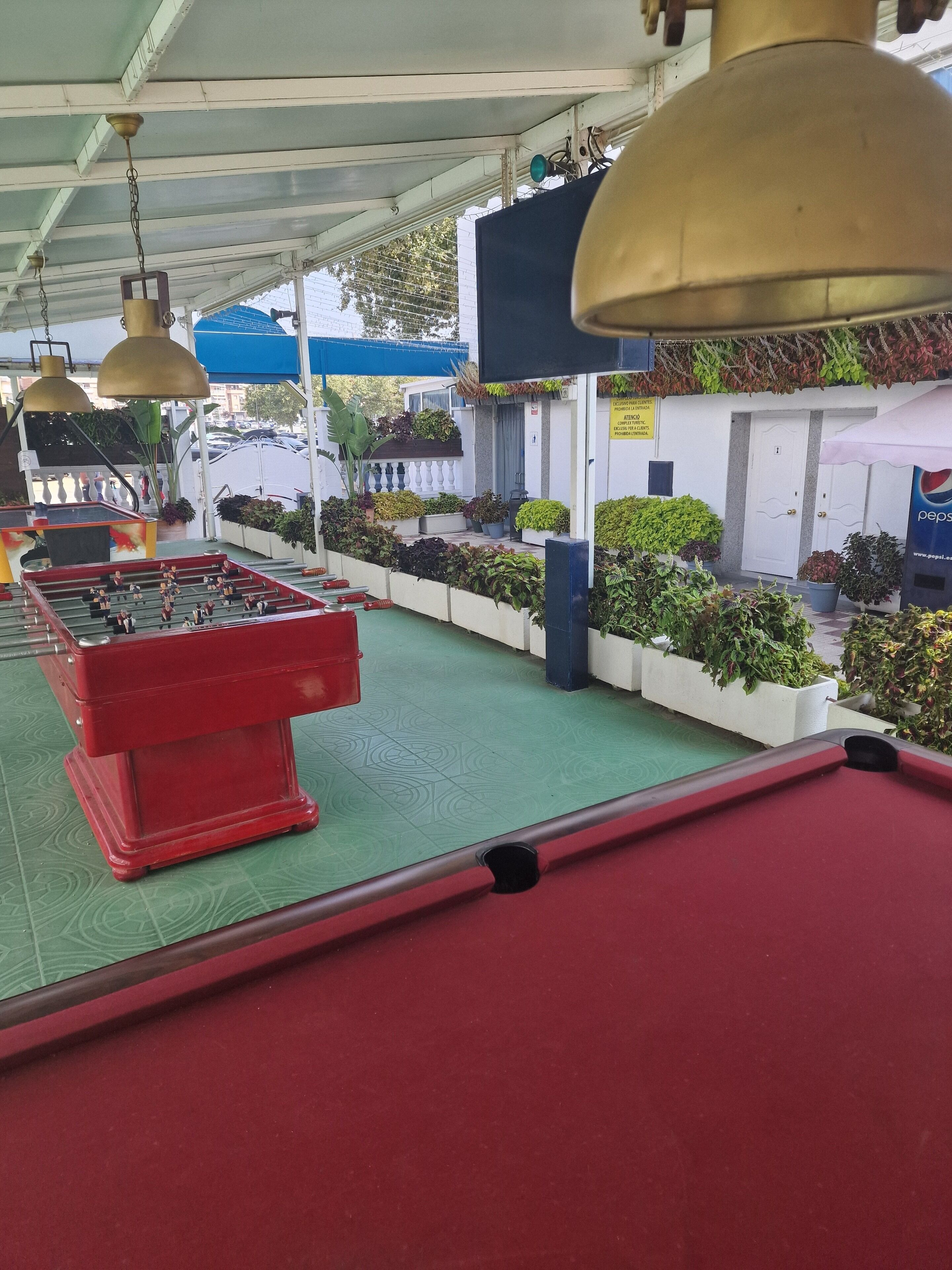 A pool table area with a red table, green felt, and hanging lamps.