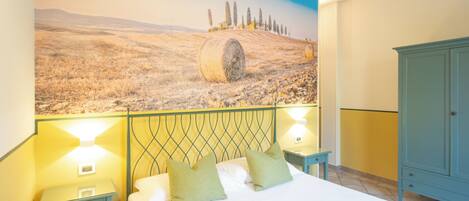 Un dormitorio con cama, dos mesitas de noche, un armario y un mural que muestra un campo con pacas de heno.