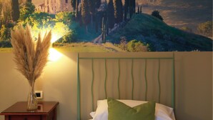 Un dormitorio con una cama, una mesita de noche, un jarrón con plantas secas y un mural de paisaje en la pared.