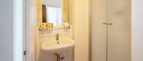 A bathroom with a white sink, mirror, and a glass shower door.