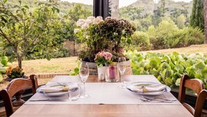 Una mesa para dos, con un centro de mesa floral, rodeada de sillas, en un entorno de jardín.