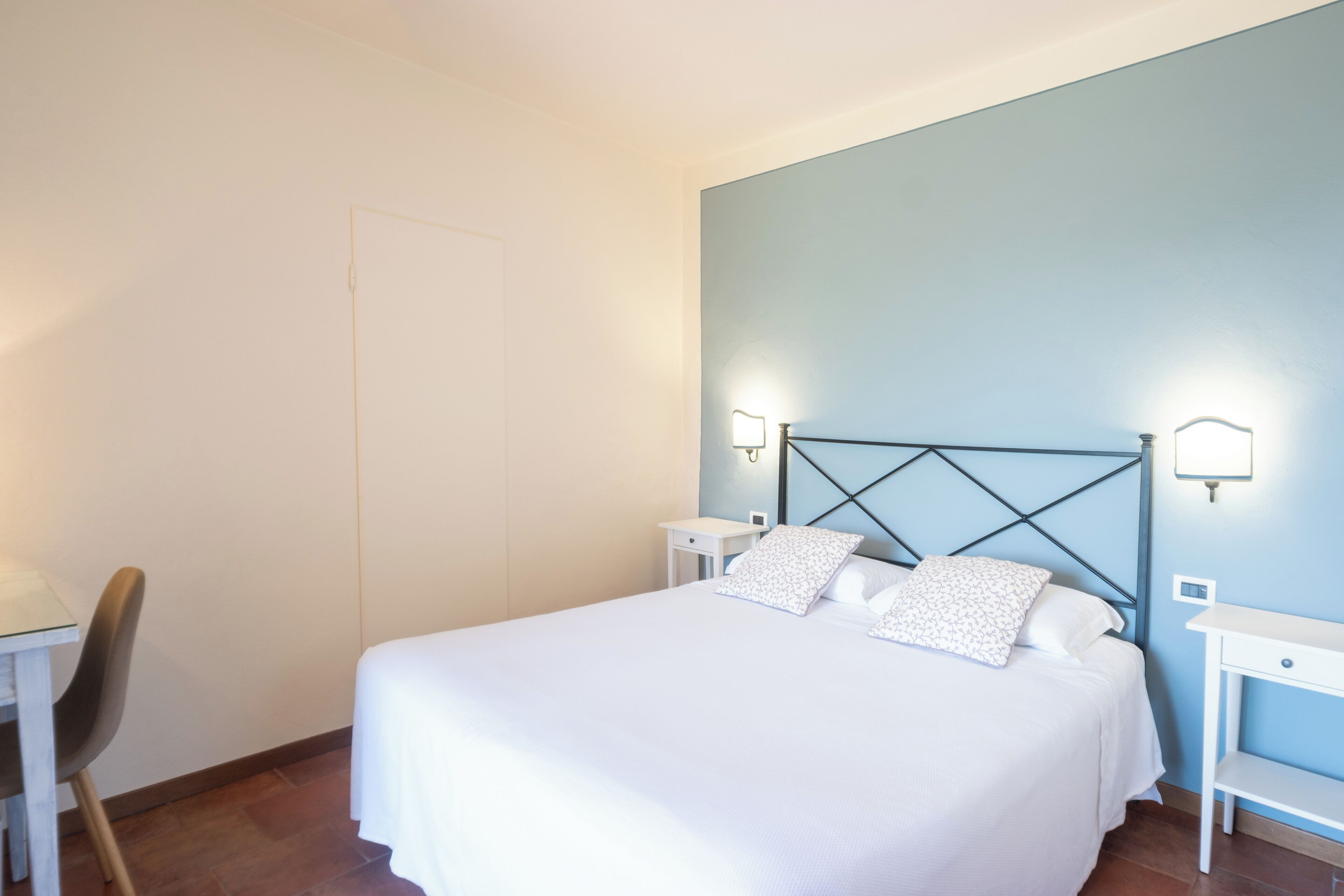 A neatly arranged bedroom with a bed, bedside tables, and a chair.
