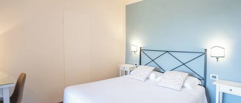 A neatly arranged bedroom with a bed, bedside tables, and a chair.