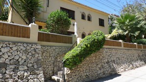 A building with a stone wall, a wooden fence, and a staircase leading up to a door. - Villa Senomar (Benissa)