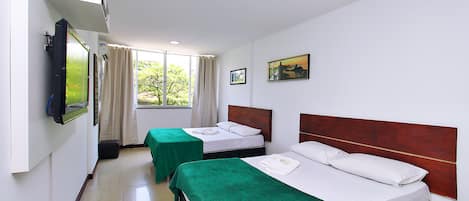 A hotel room with two beds, a television, and a window with curtains.