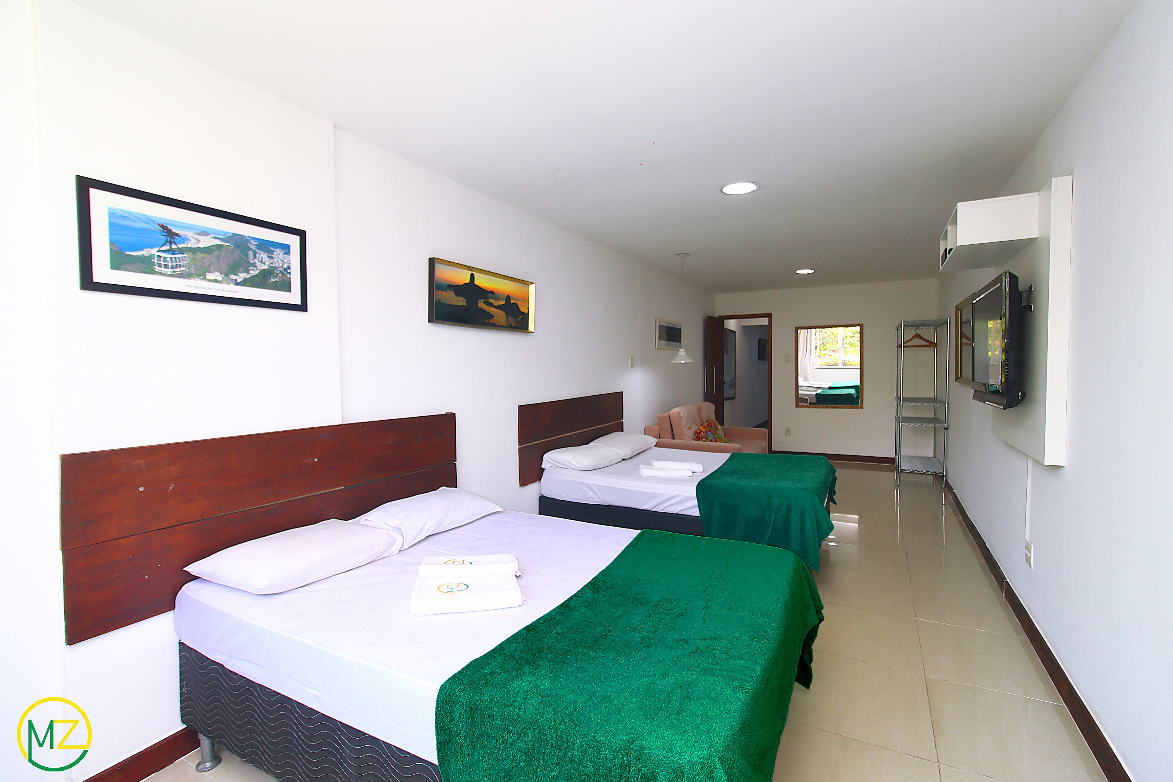 A hotel room with two beds, a television, and artwork on the walls.