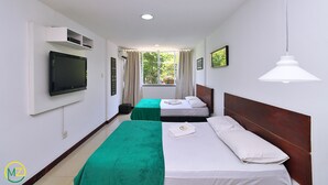 Een hotelkamer met twee bedden, een televisie, een raam met gordijnen en een hanglamp.