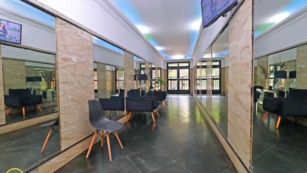 Een moderne lobby met een zithoek en een grote spiegel die de ruimte weerspiegelt.