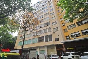 Un immeuble à plusieurs étages dont le rez-de-chaussée est occupé par des commerces, avec une devanture visible et une enseigne.