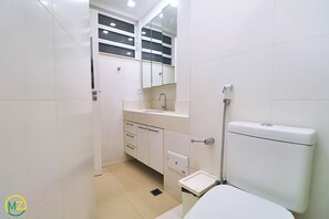 Une salle de bain équipée de toilettes, d’un lavabo, d’un miroir et de placards.