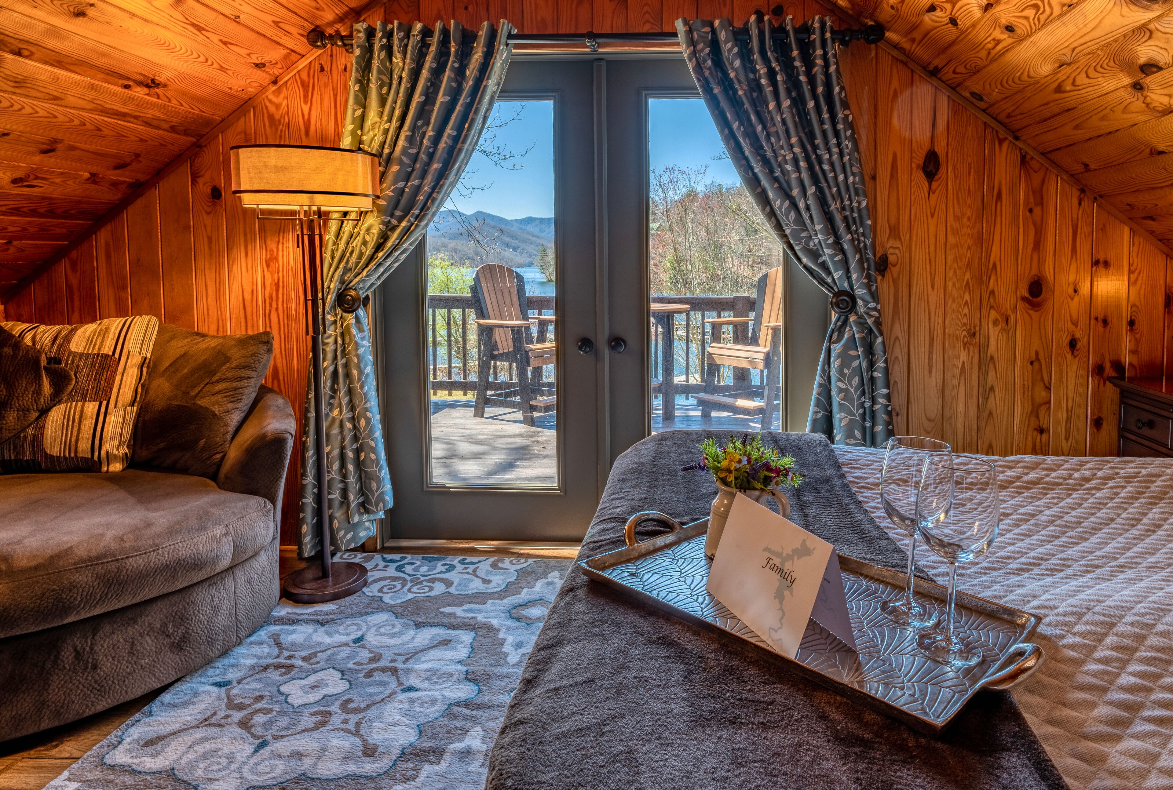A cozy room with a sofa, a small table with a tray, and a view through a glass door to an outdoor deck.