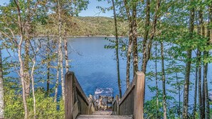 A wooden bridge leading to a dock over calm water, surrounded by trees. - stayNantahala - Smoky Mountain Cabins (Topton)