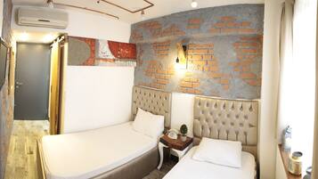 A bedroom with a brick wall, a bed, a nightstand, and a wall-mounted light.