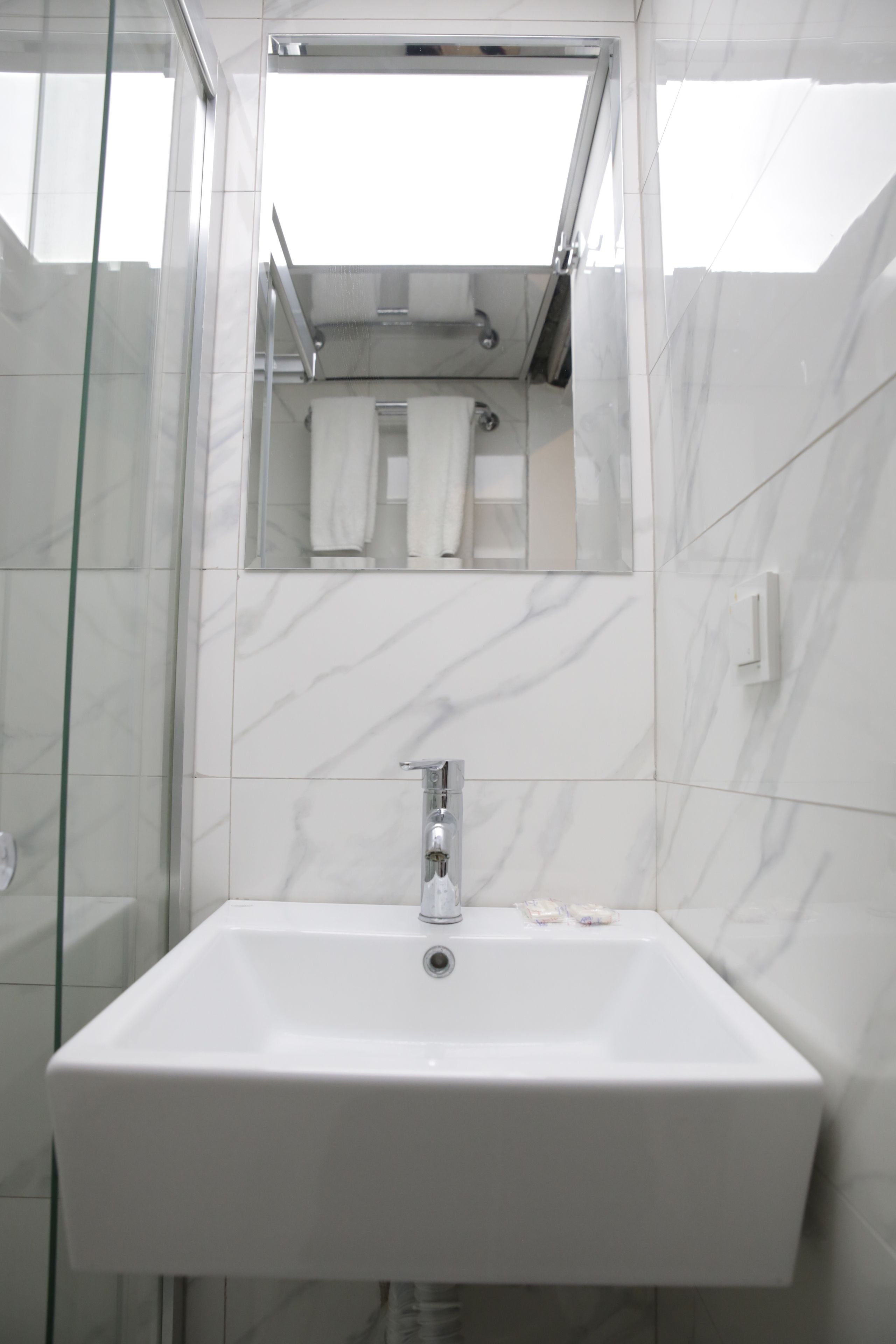 A bathroom with a white sink, a glass shower enclosure, and a mirror above the sink.