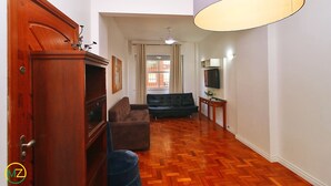 Un salon avec un plancher en bois, un canapé, une télévision et une lampe.