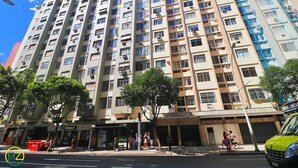 Un immeuble résidentiel à plusieurs étages, doté de balcons, avec une devanture visible et une rue devant.