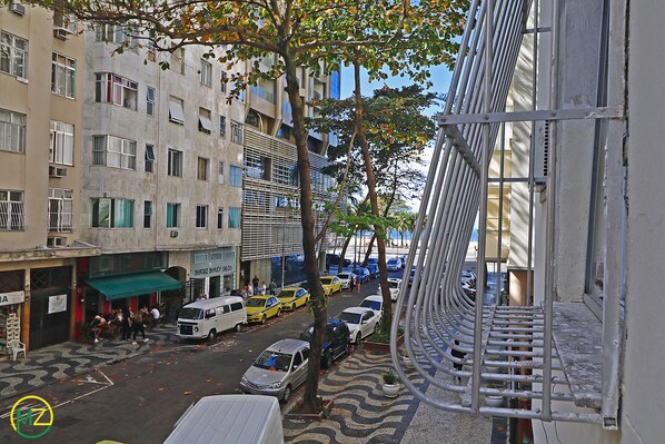A street view with buildings, parked cars, and a tree.