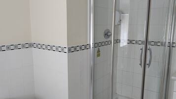 Un baño moderno con ducha de vidrio, paredes de azulejos blancos y suelo de mármol.