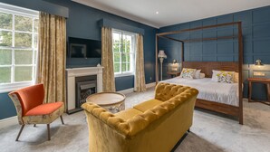 A bedroom with a four-poster bed, a fireplace, a television, and a large window with curtains. - The Northwick Arms (Evesham)