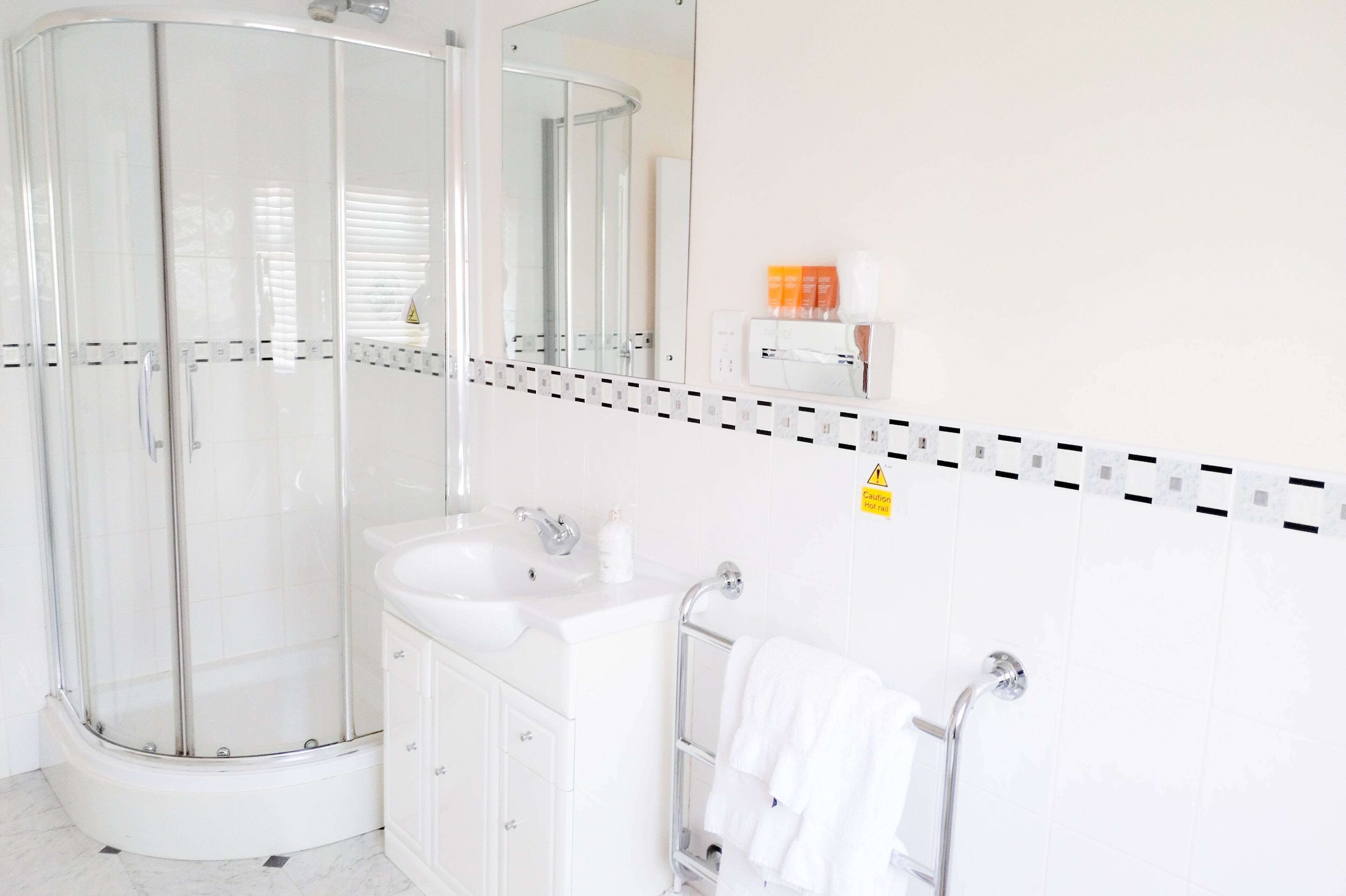Une salle de bain moderne avec une douche à parois de verre, un lavabo et un porte-serviettes.