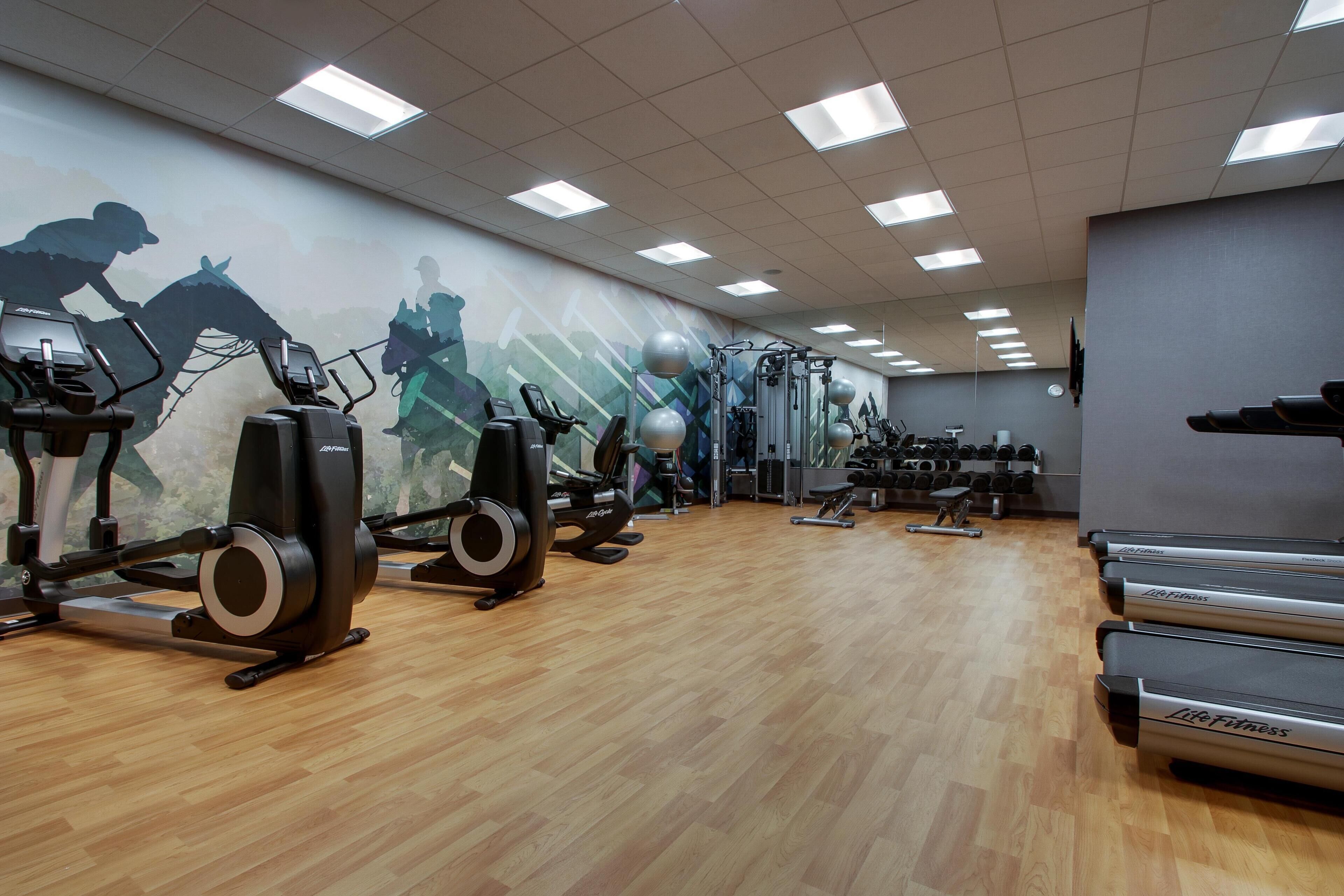 Un gimnasio con cintas de correr, elípticas y equipo de levantamiento de pesas.