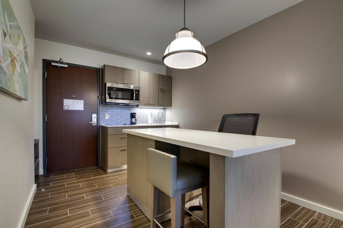 A modern kitchen with a microwave, coffee maker, and a pendant light.