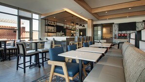 A modern restaurant with high ceilings, large windows, and a variety of seating options including tables, booths, and a long counter.