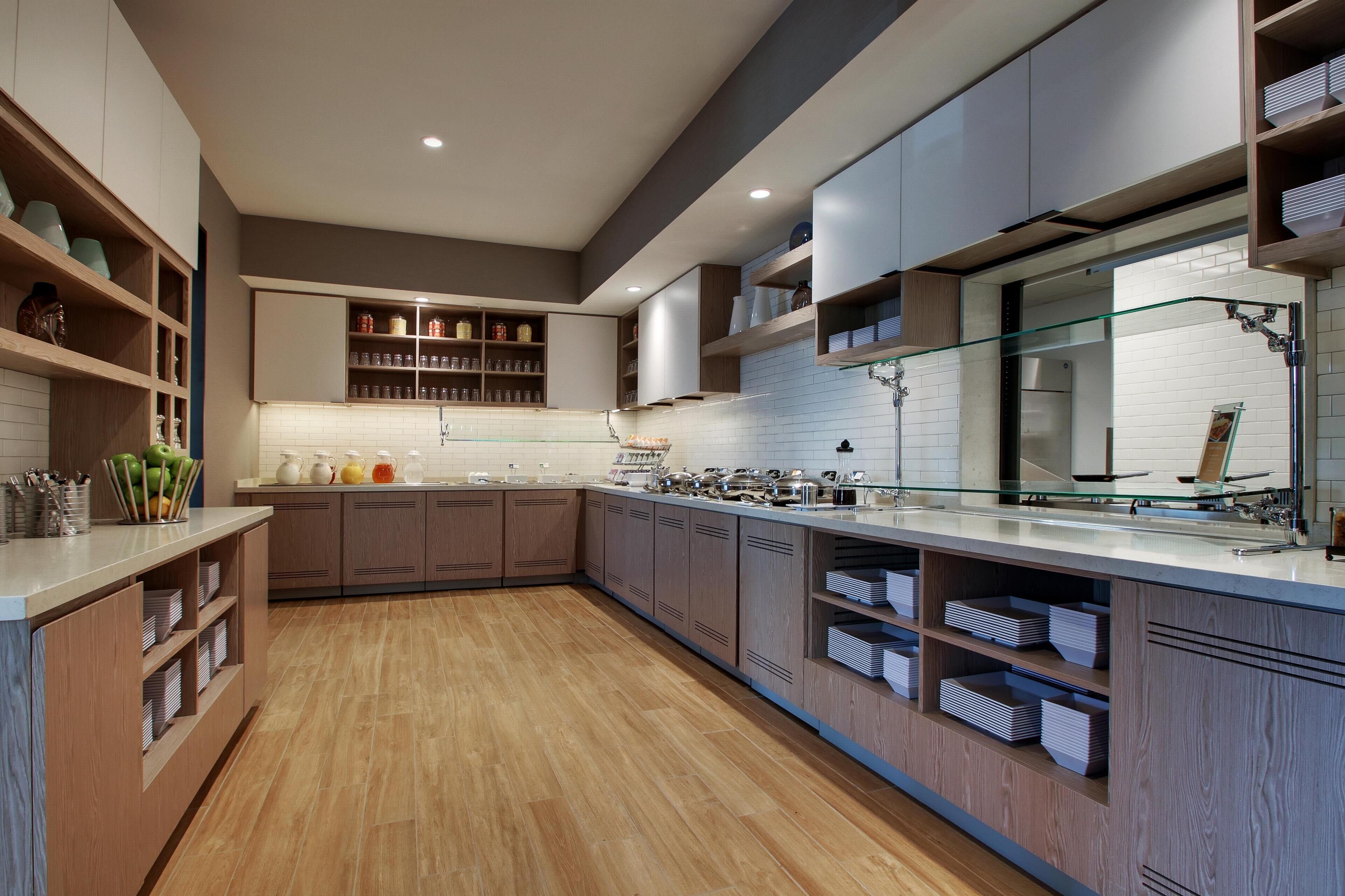 A modern kitchen with wooden cabinets, a glass backsplash, and built-in shelves.