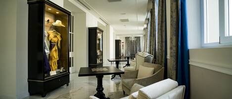 A spacious living area with a marble floor, a display cabinet with clothing, a table with chess pieces, and a comfortable seating area.