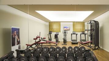 A gym with various exercise equipment, including treadmills, a weight bench, and dumbbells.