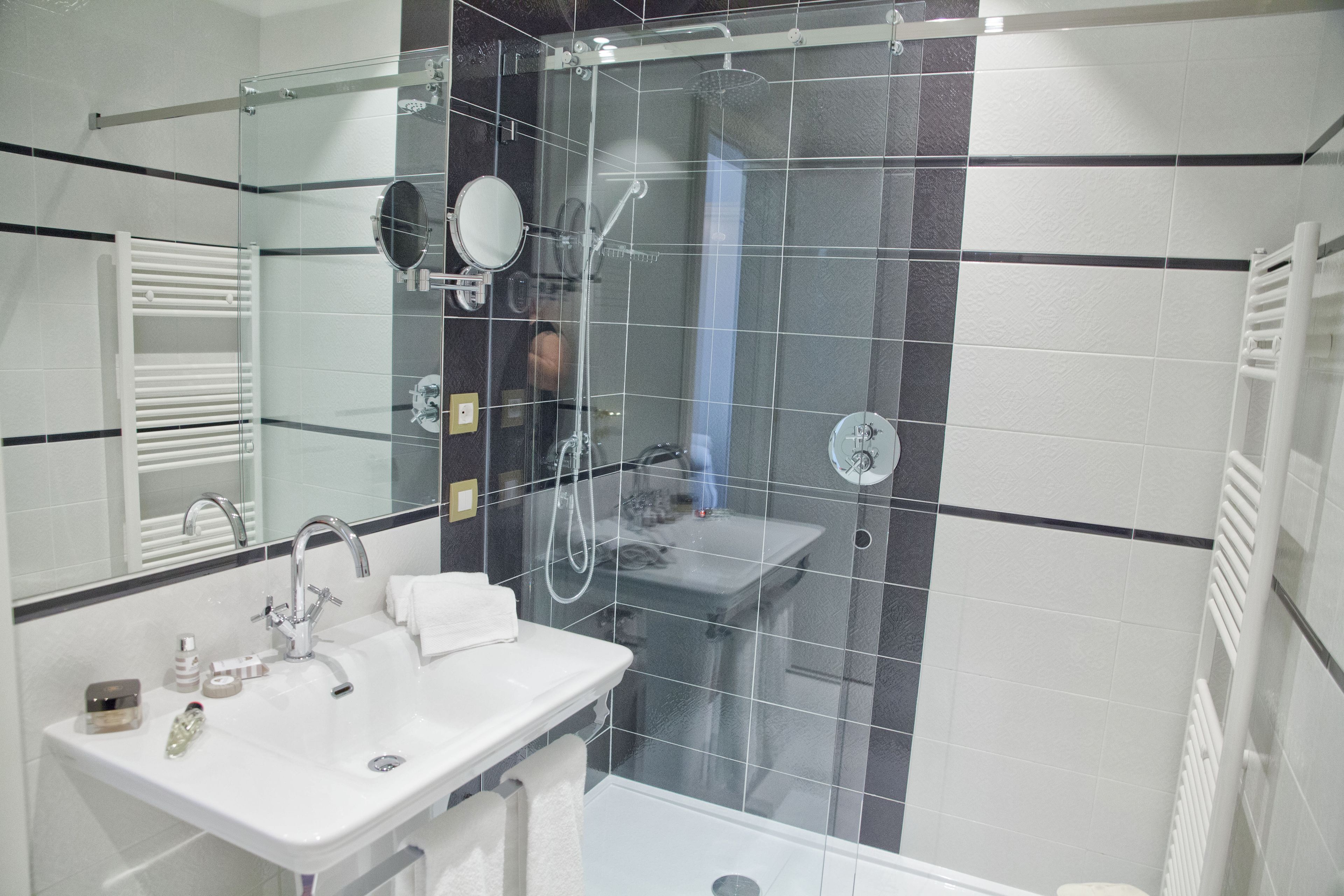 Ein modernes Badezimmer mit einer begehbaren Glasdusche, einem weißen Waschbecken und einem Spiegel.