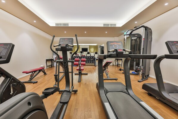 Un gimnasio con cintas de correr, elípticas y equipo de levantamiento de pesas.