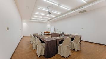 A conference room with a long table, chairs, a projector, and a whiteboard.