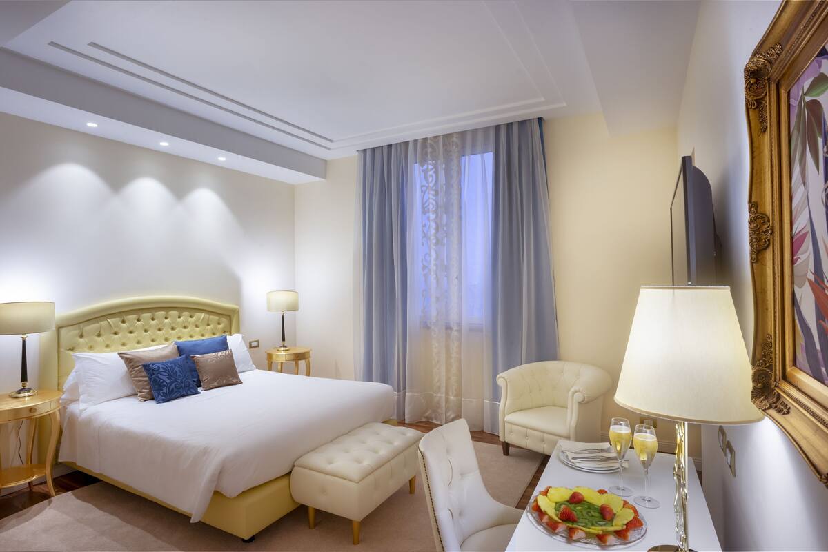 Een hotelkamer met een groot bed, een zithoek met een tafel, een televisie en een schilderij aan de muur.