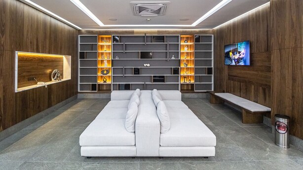Sala de estar moderna com sofá branco, estantes embutidas e uma TV de tela plana.