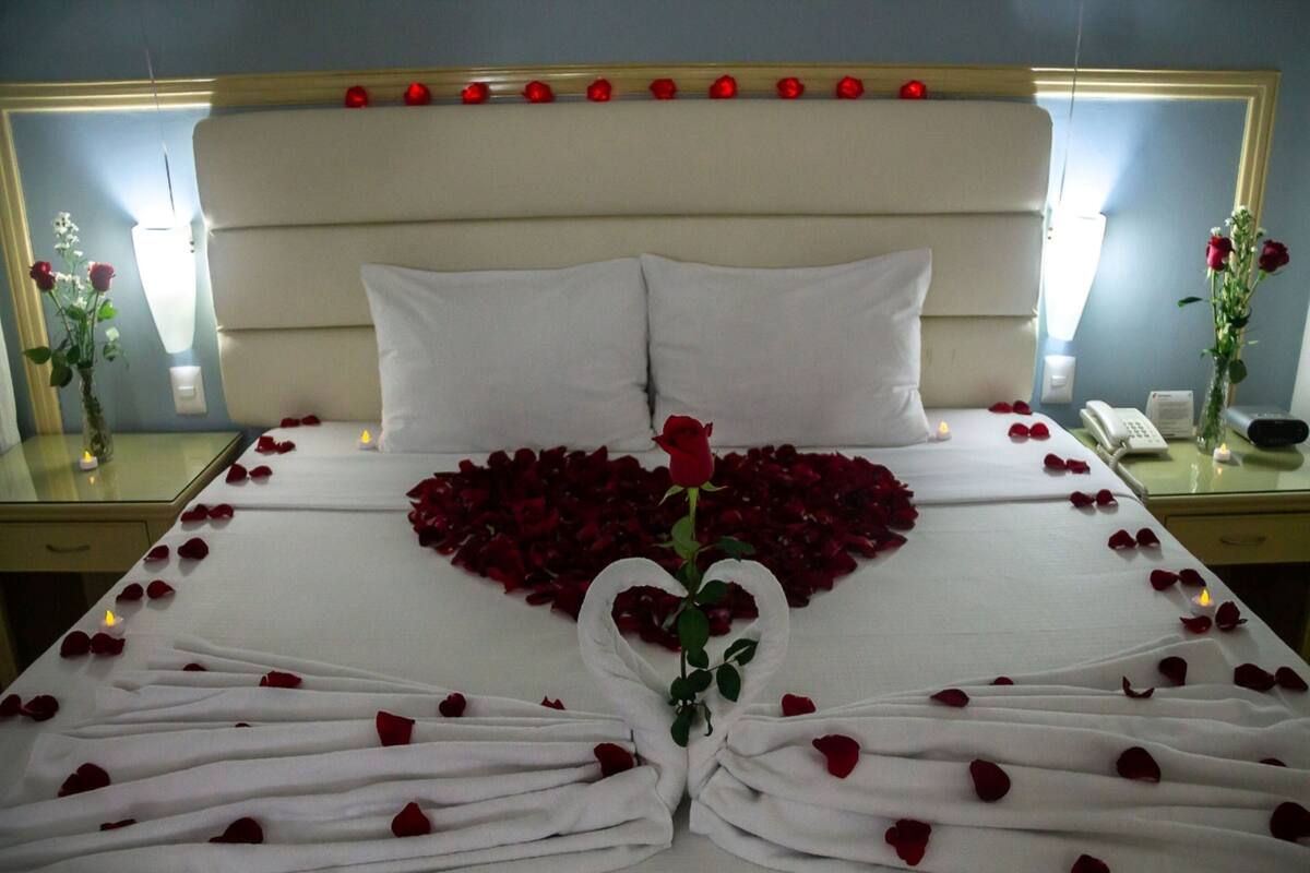 Ein Bett mit Rosenblättern, die ein Herz formen, und einer einzelnen Rose in der Mitte.