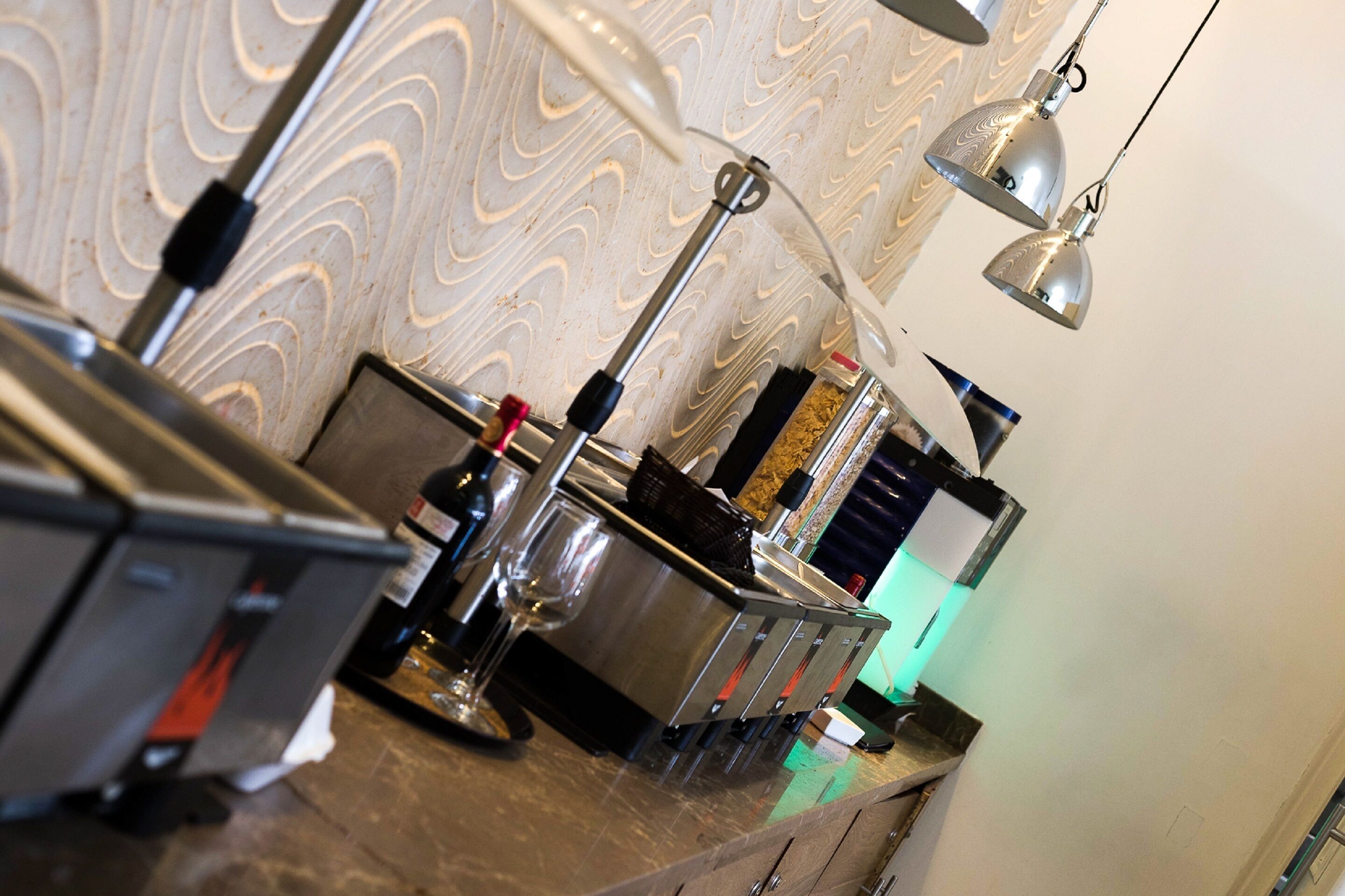 A kitchen counter with various appliances and a patterned wall in the background.