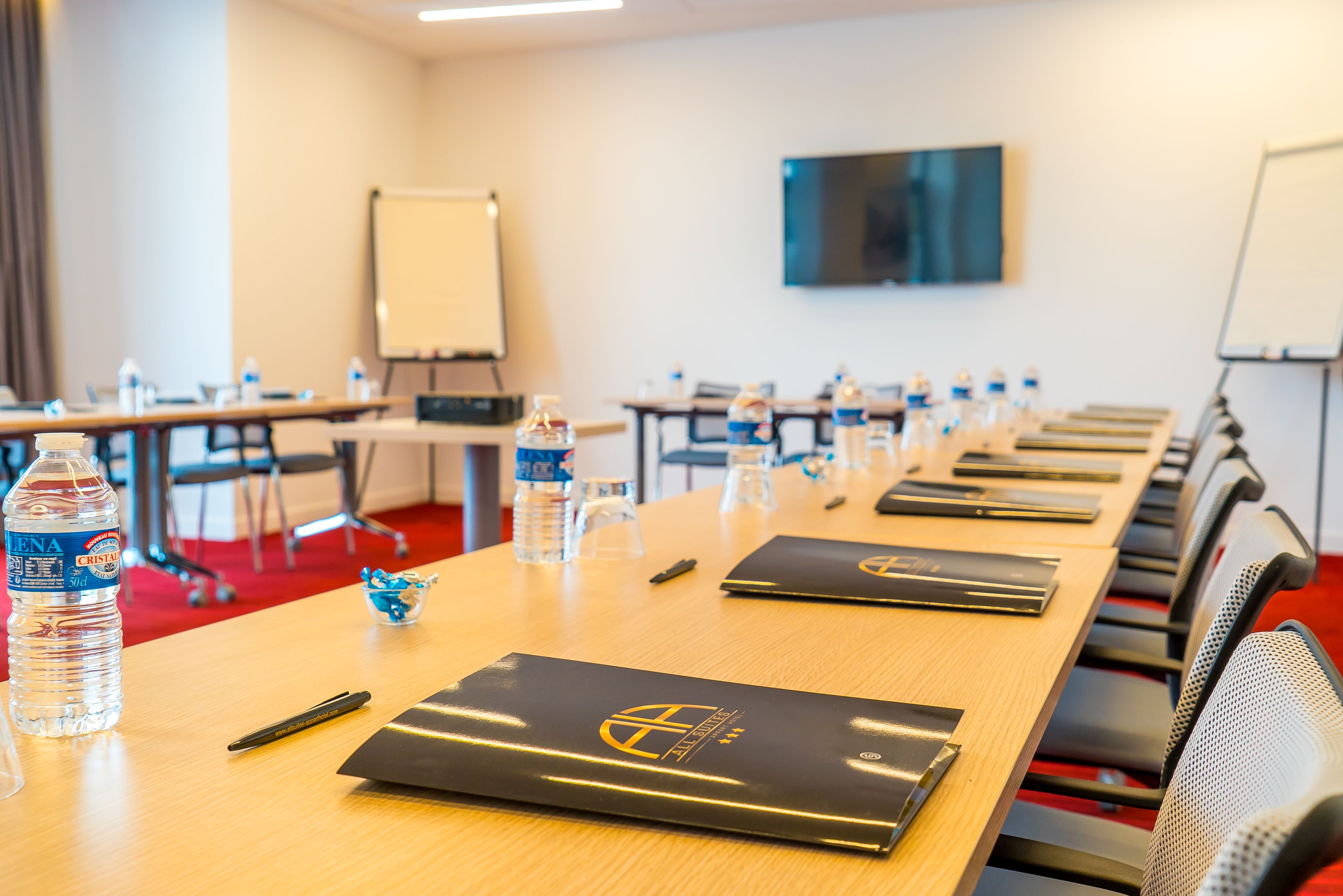 Een vergaderruimte met een lange tafel, waterflesjes, notitieboekjes en een projectiescherm.
