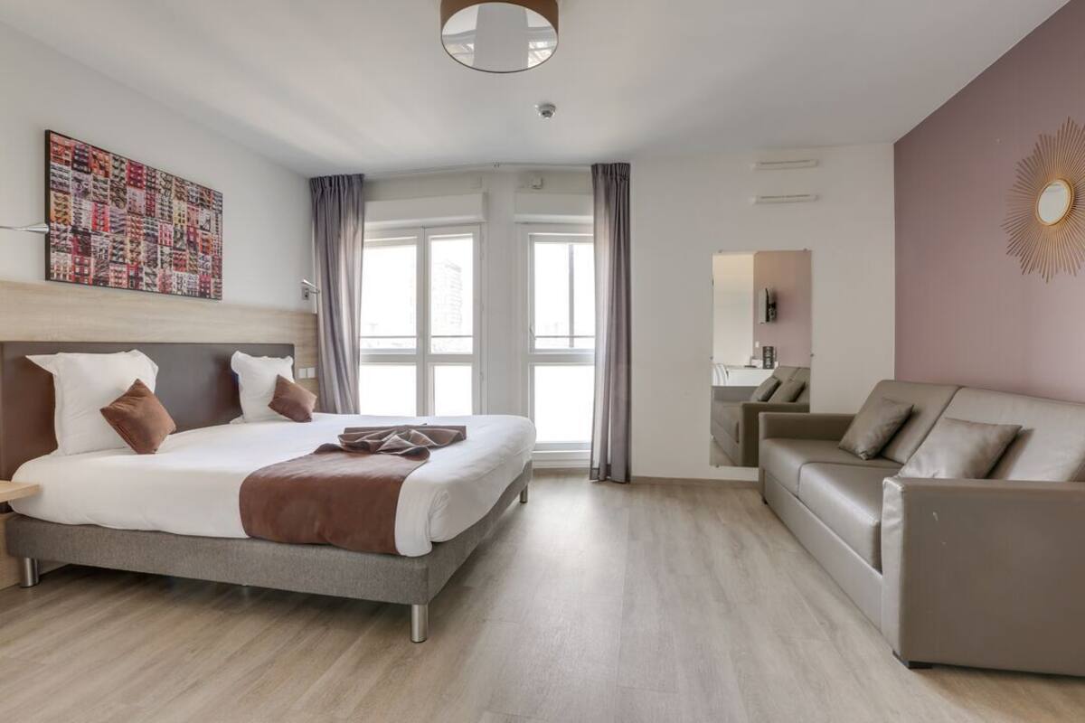 Une chambre d’hôtel moderne dotée d’un grand lit, d’un canapé, d’une salle de bain et offrant une vue sur la ville.