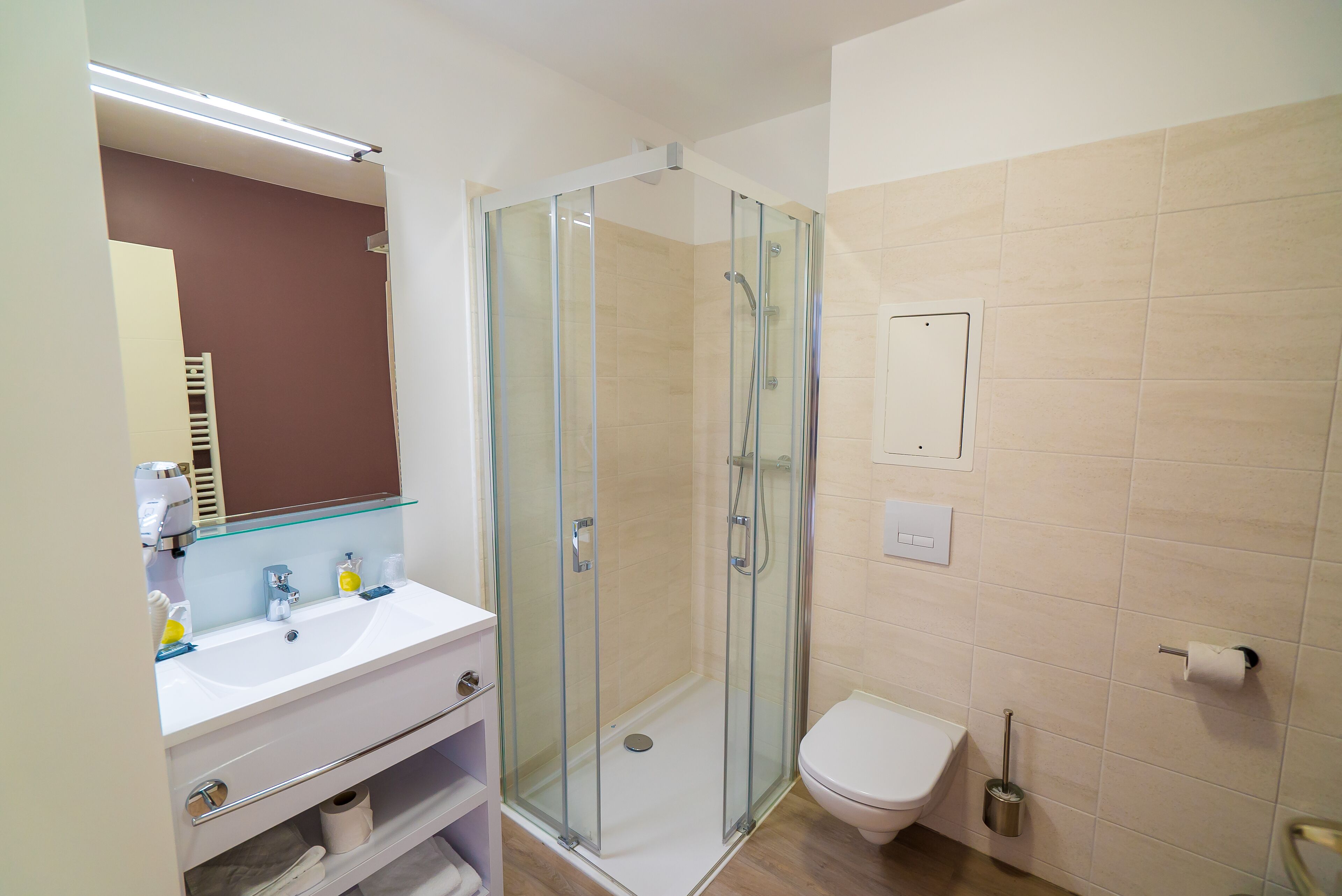 A modern bathroom with a glass-enclosed shower, a white sink, and a toilet.
