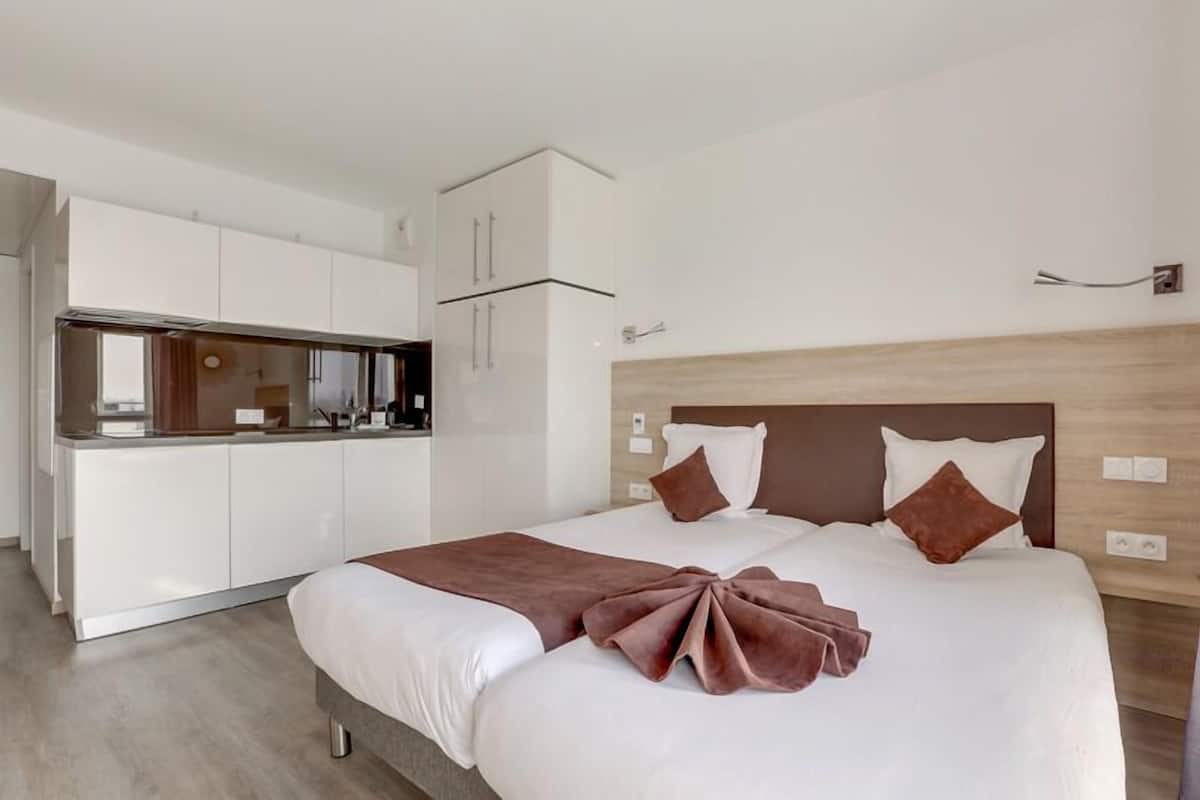 Ein modernes Hotelzimmer mit einem Bett, einer Küchenzeile und einem hölzernen Kopfteil.