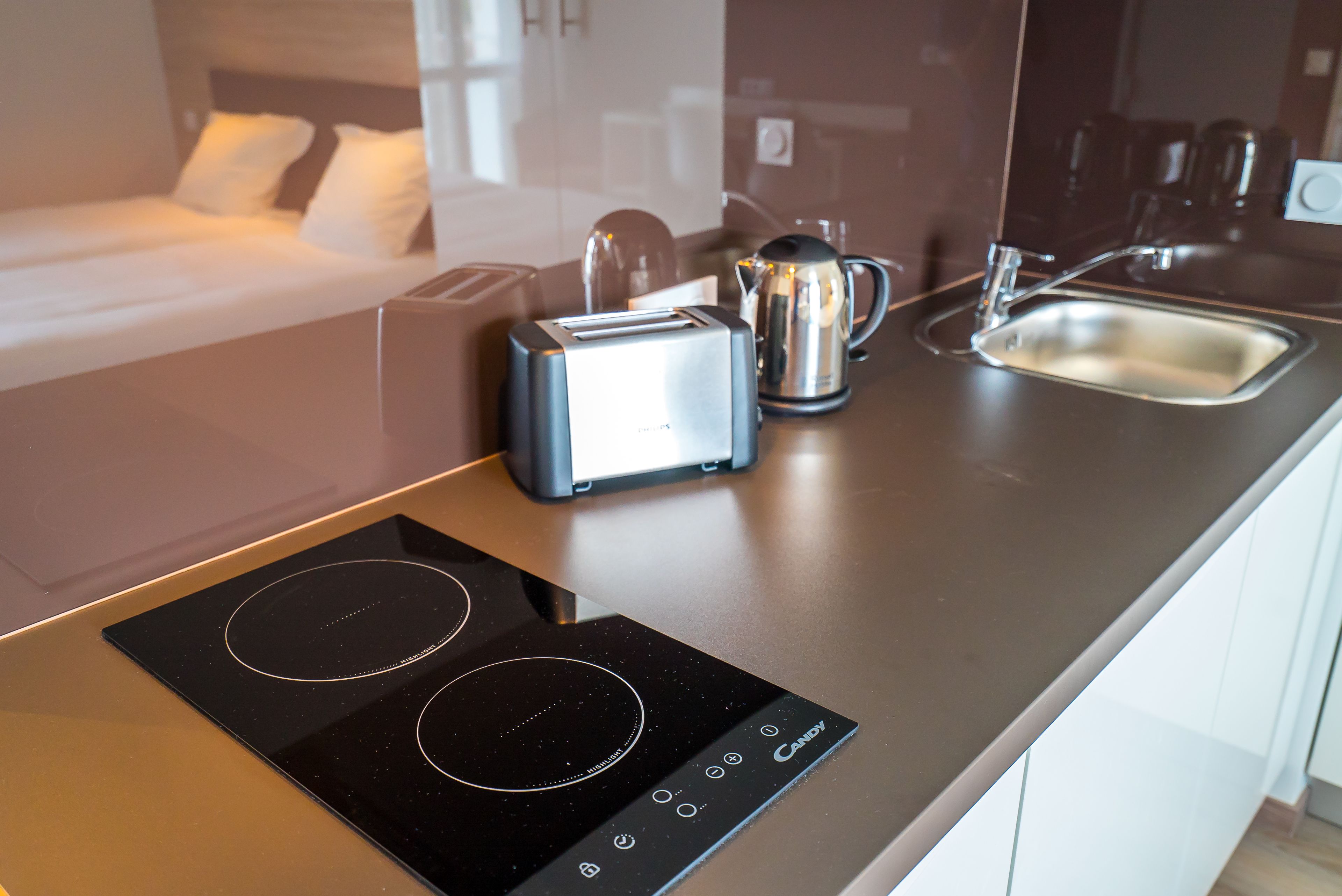 A modern kitchen with an induction cooktop, a toaster, and a kettle.