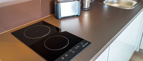 A modern kitchen with an induction cooktop, a toaster, and a kettle.